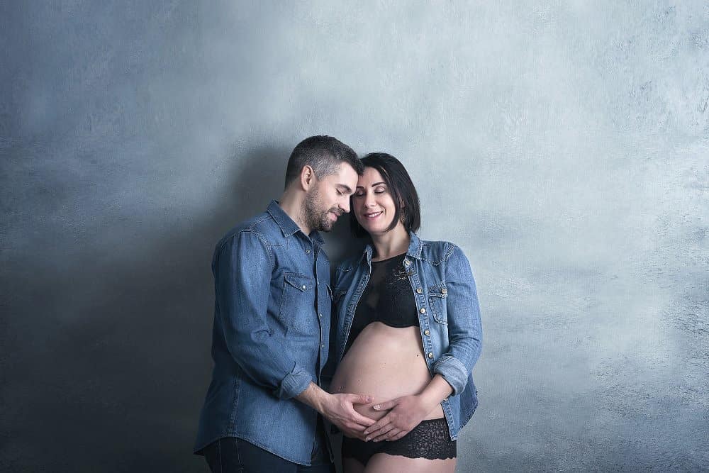 séance photo grossesse en couple devant fond photo peint à la main