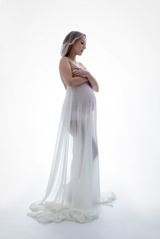 photo de grossesse avec voilage blanc transparent sur fond blanc