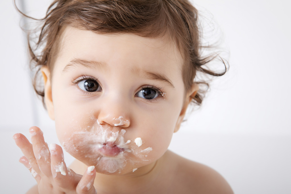 bébé avec la bouche peine de crème pendant séance photo smash the cake